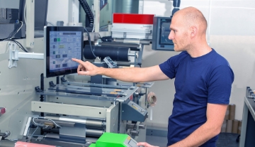 Man touching computer screen in a factory setting